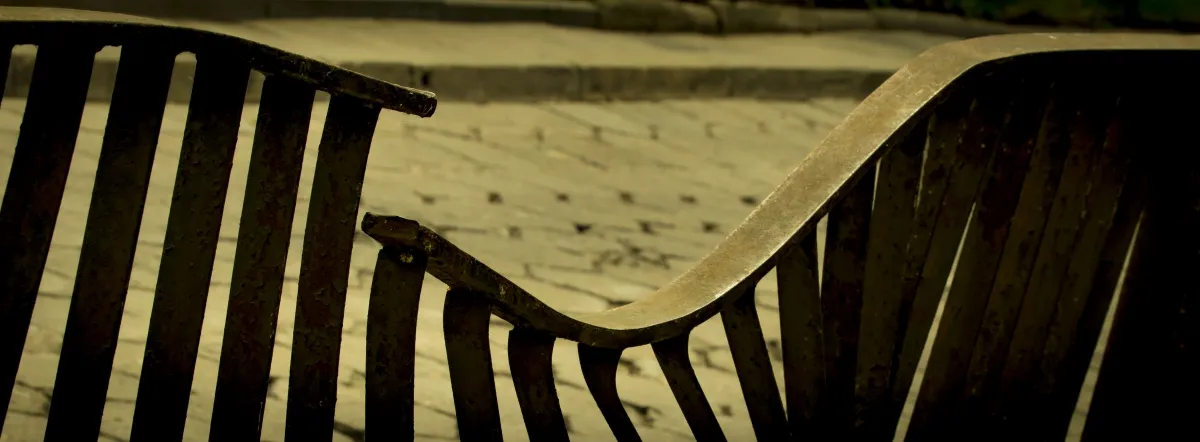 Curved park bench glowing in yellow light and shadow